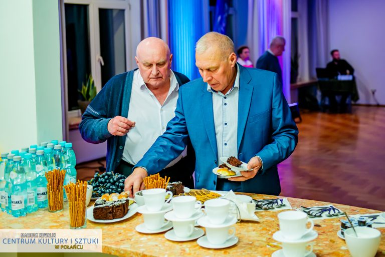 Na stole dwóch mężczyzn nakładających sobie ciasto