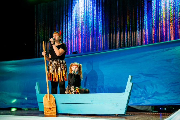 Widowisko taneczno-muzyczne "Mam tę moc" - dwie śpiewające dziewczyny płynące łódką wśród materiałów imitujących morską wodę