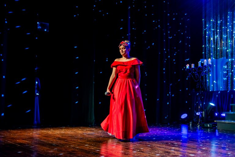 Widowisko taneczno-muzyczne "Mam tę moc" - dziewczyna w czerwonej przechadza się po scenie