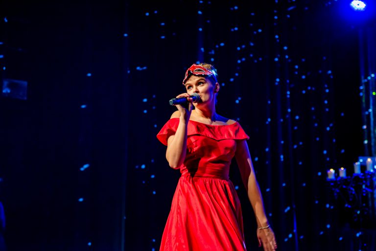 Widowisko taneczno-muzyczne "Mam tę moc" - dziewczyna w czerwonej sukni śpiewa piosenkę