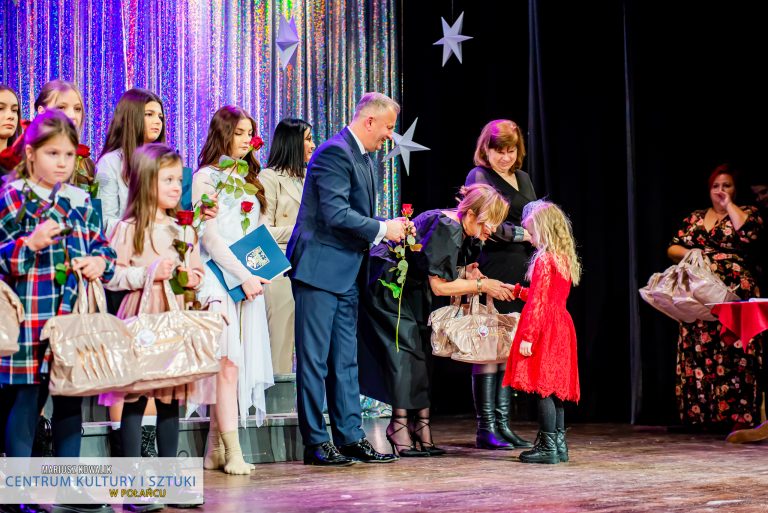 Burmistrz Połańca, dyrektor CKiSz, Skarbnik gminy wręczają różę i upominek dla młodych tancerek