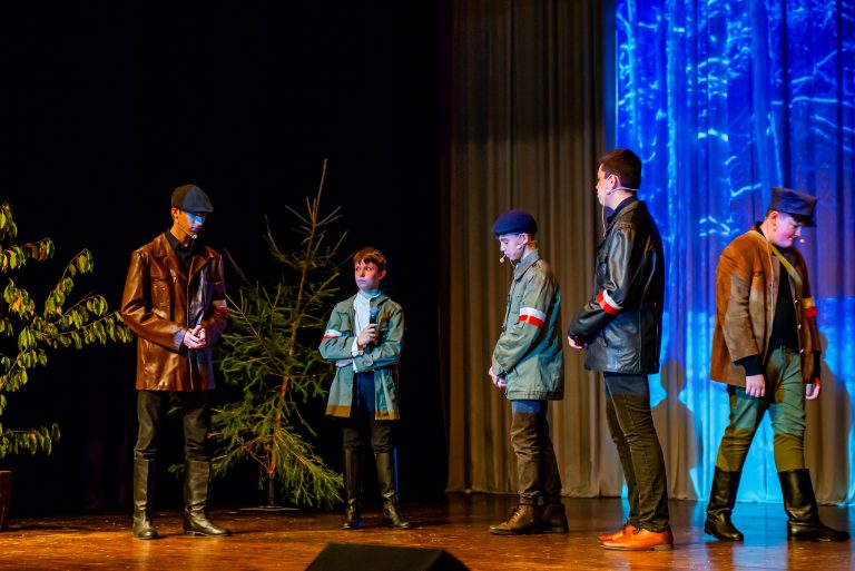 Na zdjęciu grupa młodych chłopców znajdująca się na scenie , odgrywająca scenę ze spektaklu