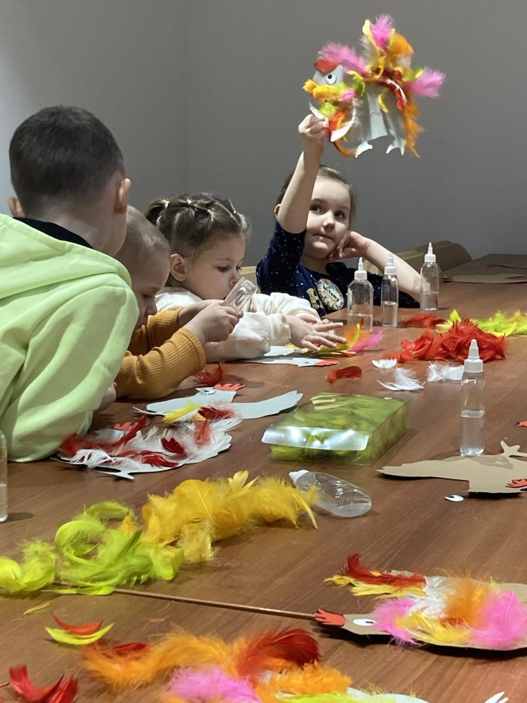 Zajęcia plastyczne z motywem świątecznym - dzieci tworzą wielkanocne kury z piórami 