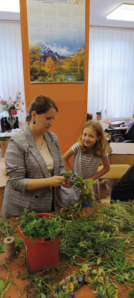 Mama z córką wyplatające wianek z kwiatów polnych i zbóż