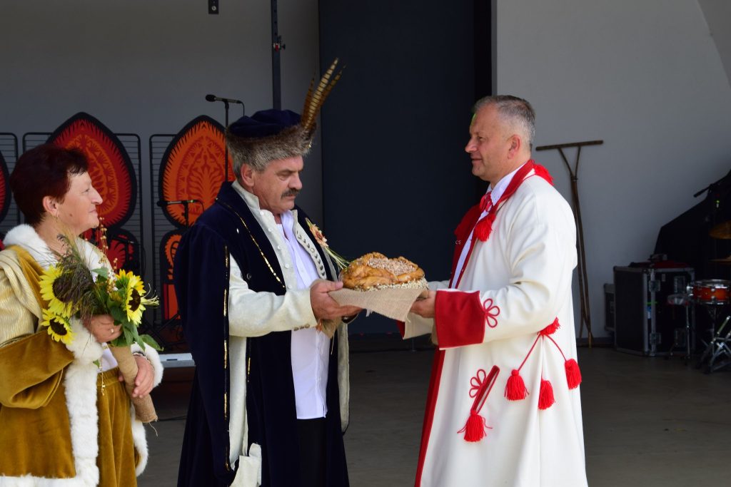 Burmistrz odbierający chleb od starosty dożynek